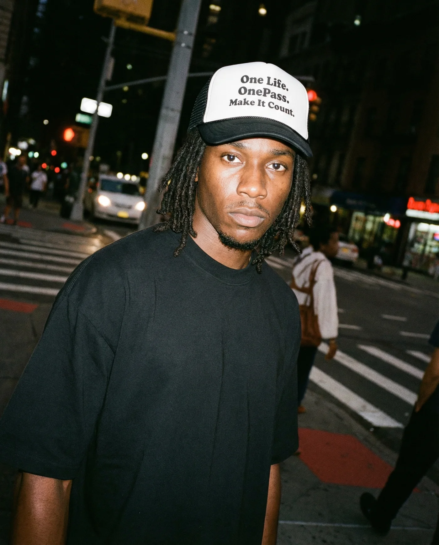 OnePass model wearing the Make It Count trucker hat at night